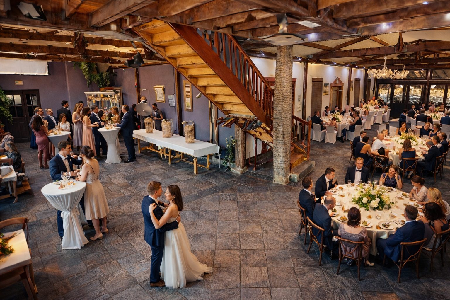 Vue intérieure panoramique de la salle du Domaine des Cascades près d’Arras, montrant l’escalier central, l’espace cocktail et les tables de réception dressées pour un mariage.